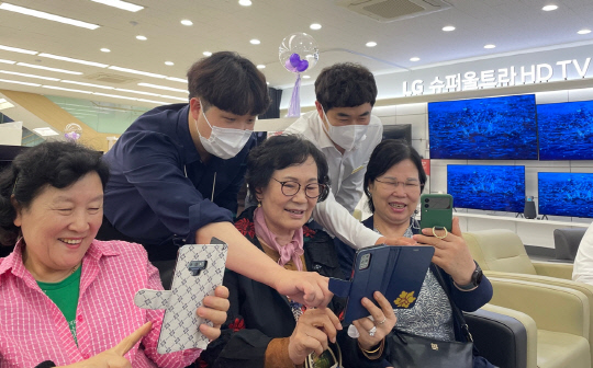 지난 22일 경기도 용인시 수지구 LG베스트샵 수지점에서 지점장과 모바일 매니저가 어르신들에게 스마트폰 활용법을 교육하고 있다.  LG전자 제공